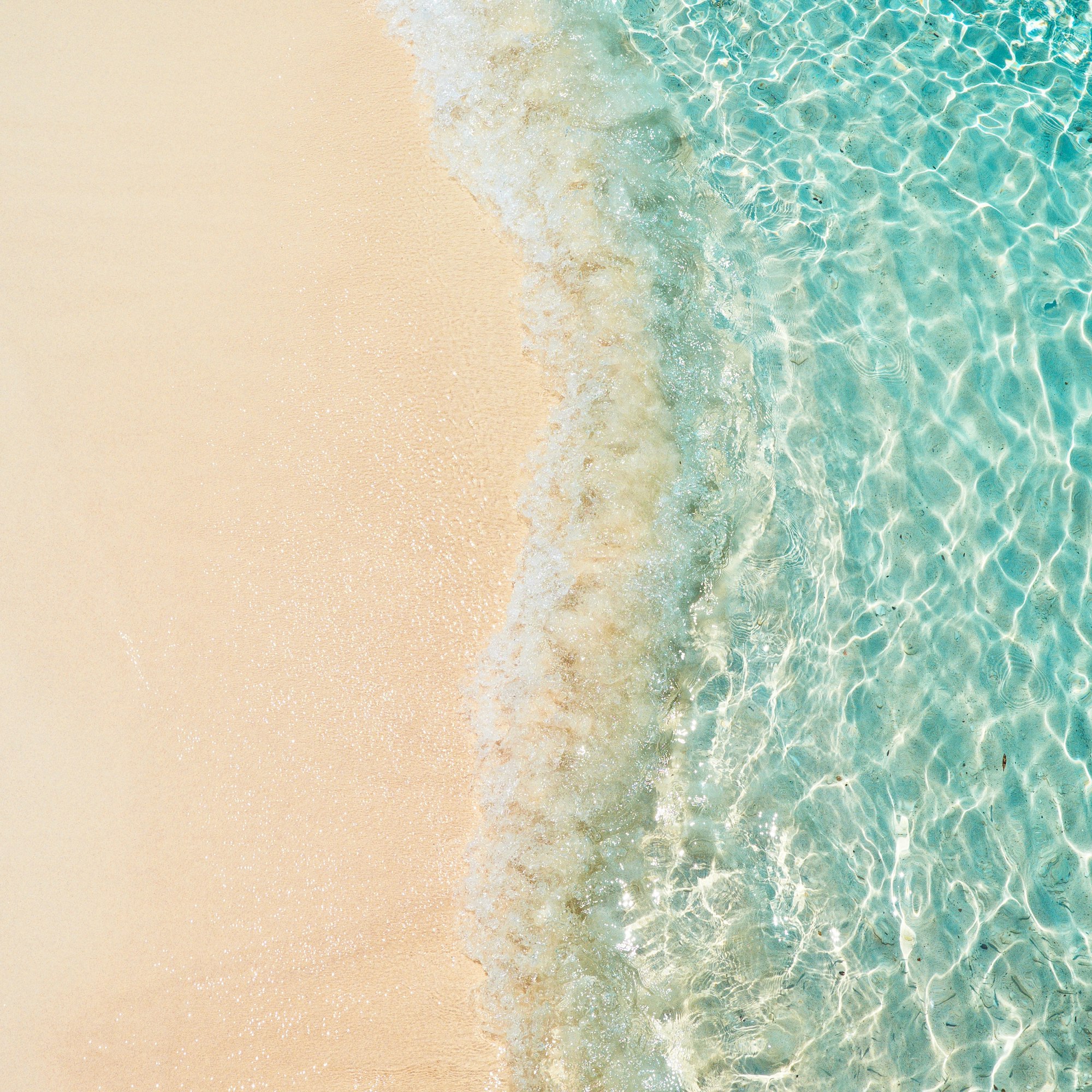 Turquoise wave washing over golden sand